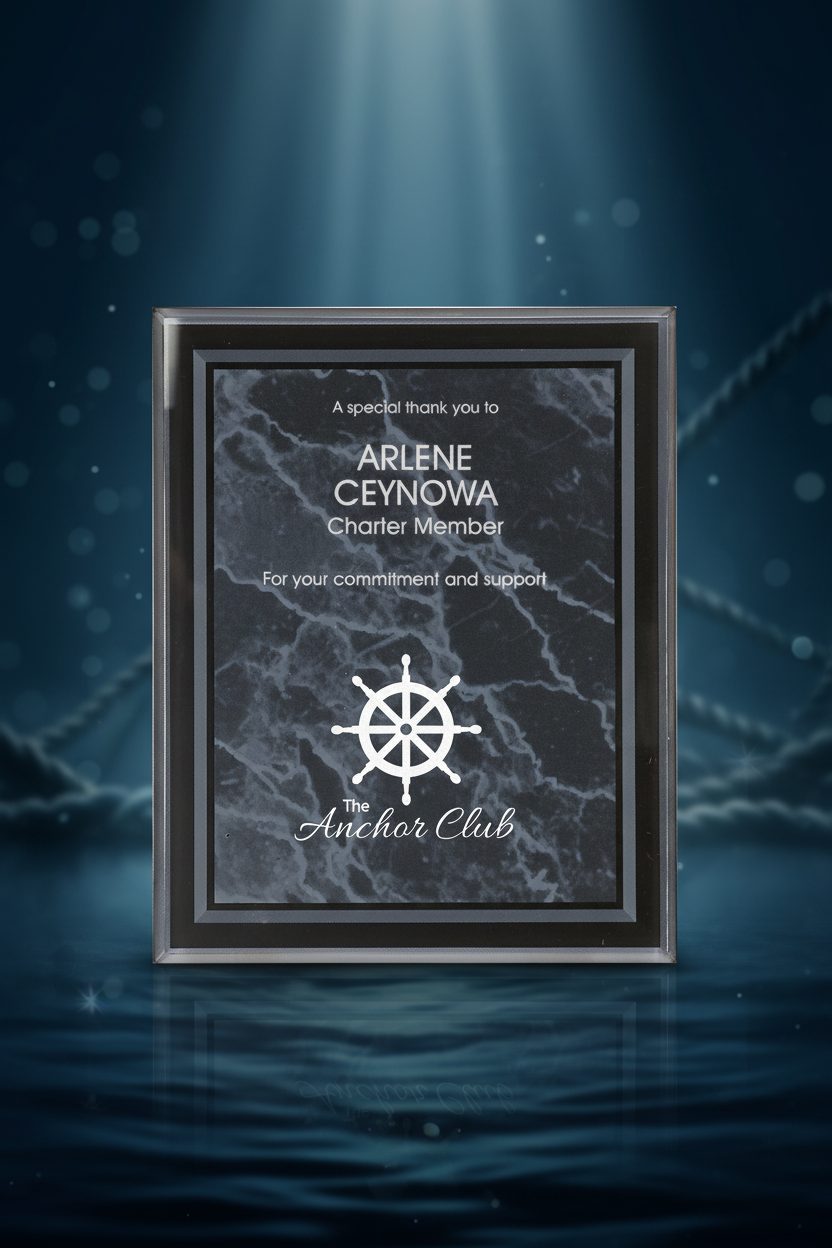 Plaque with engraved text and a ship's wheel symbol, presented in a black frame.